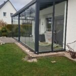 Modernes Vordach mit schwarzem Gestell und Glasschiebetüren zum Hauseingang