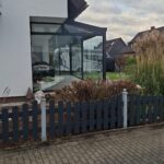 Modernes Terrassendach mit schwarzem Gestell und Glasschiebewand, moderne Architektur mit Außenbereich