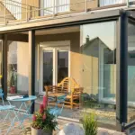 Kompakter Kaltwintergarten in Anthrazit mit geöffneter Ganzglasschiebeanlage und Blick in den Garten