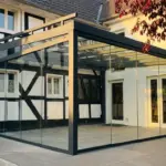 Freistehender Kaltwintergarten in Anthrazit mit Ganzglasschiebeanlagen an historischem Fachwerkhaus