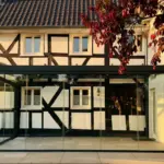 Freistehender Kaltwintergarten in Anthrazit mit Ganzglasschiebeanlagen an historischem Fachwerkhaus